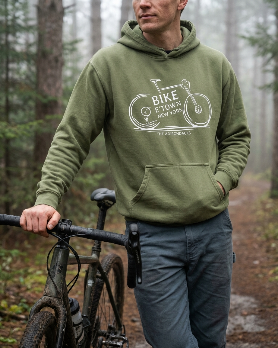 Person wearing a green hoodie with a bike graphic in a forest setting