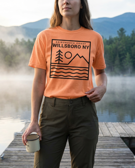 Person wearing an orange t-shirt with 'Willsboro NY' design by a lake