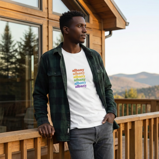 Man wearing a white t-shirt with 'albany' printed in colorful letters on a wooden deck.