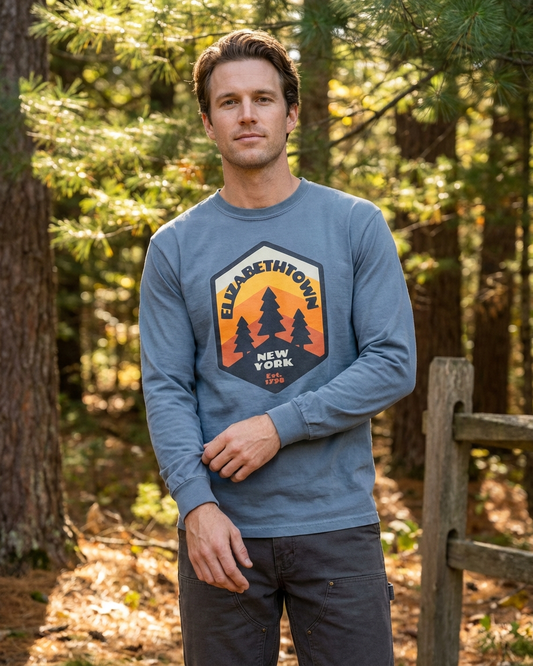 Man wearing a blue sweatshirt with an elizabethtown New York  tree graphic in a forest setting
