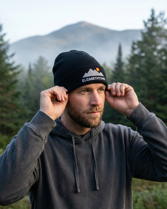 Man wearing a black beanie with 'Elizabethtown' text in a forest setting