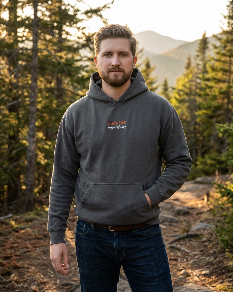Man wearing a gray hoodie with a "fuck off respectfully" logo in a forest setting