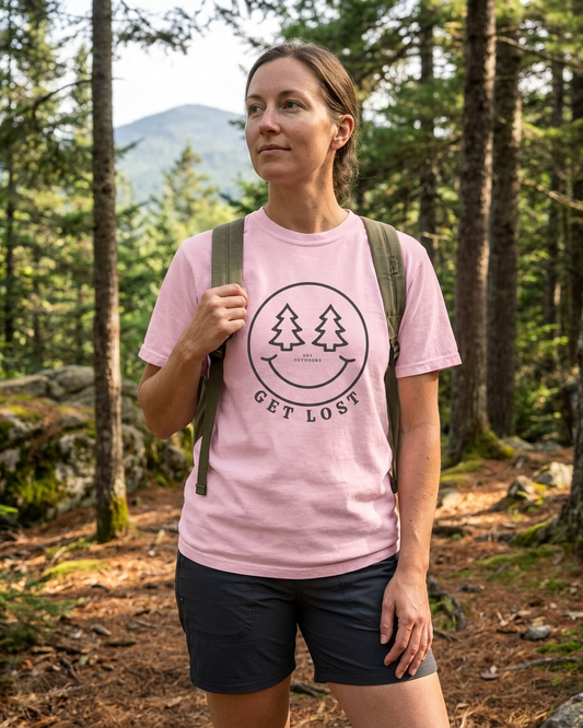 Person hiking in a forest wearing a pink t-shirt with a nature-themed smile design.