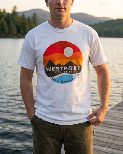 Person wearing a white t-shirt with a colorful  Westport New York graphic design standing by a lake.